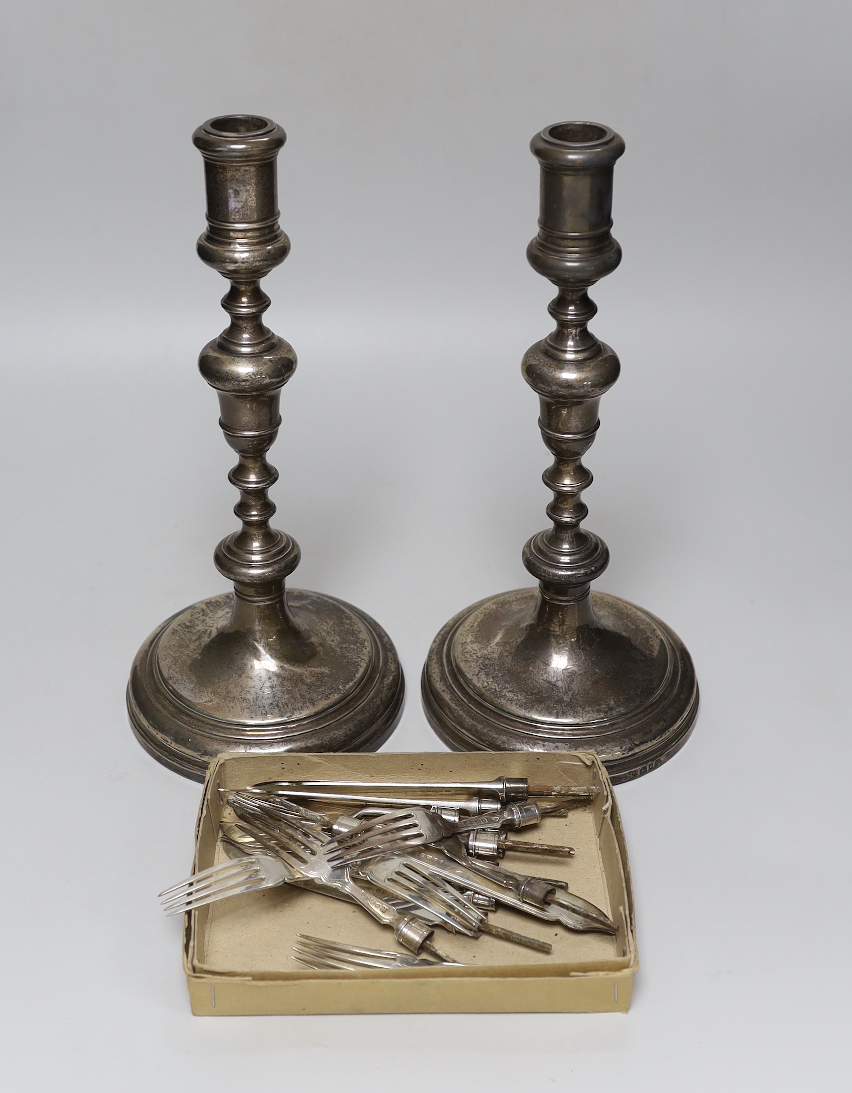 A pair of George V silver candlesticks, by William Comyns & Sons Ltd, London, 1930, height 29.6cm, weighted and eight pairs of silver fish eaters (no handles).